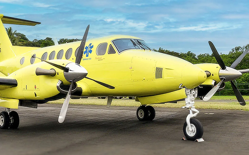 A close-up front-side view of a yellow twin-engine turboprop air ambulance on the tarmac.