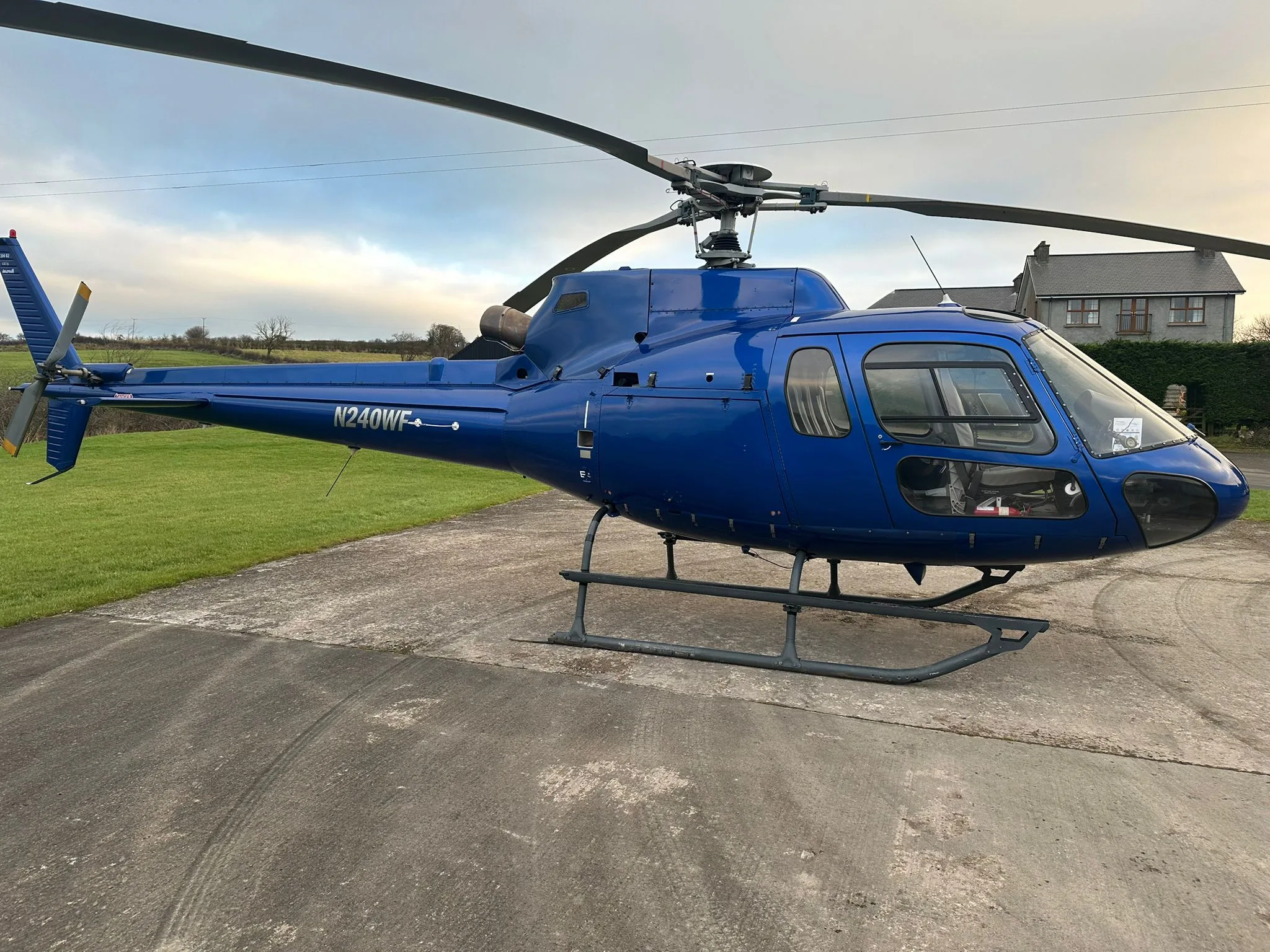 Side view of the blue N240WF helicopter parked on the ground.