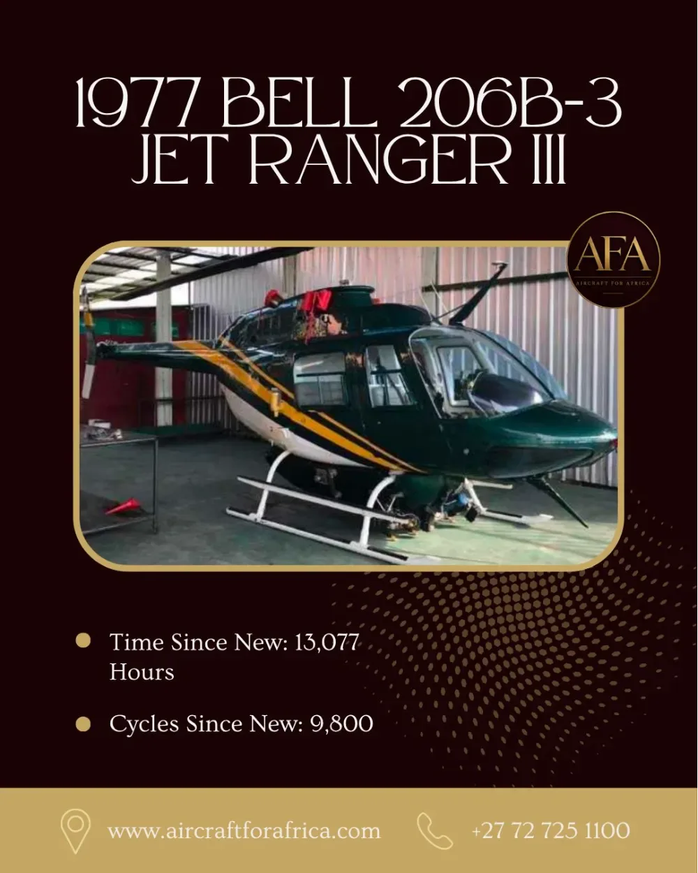 A dark green and white Bell 206B-3 Jet Ranger III helicopter with a yellow stripe is parked inside a hangar.