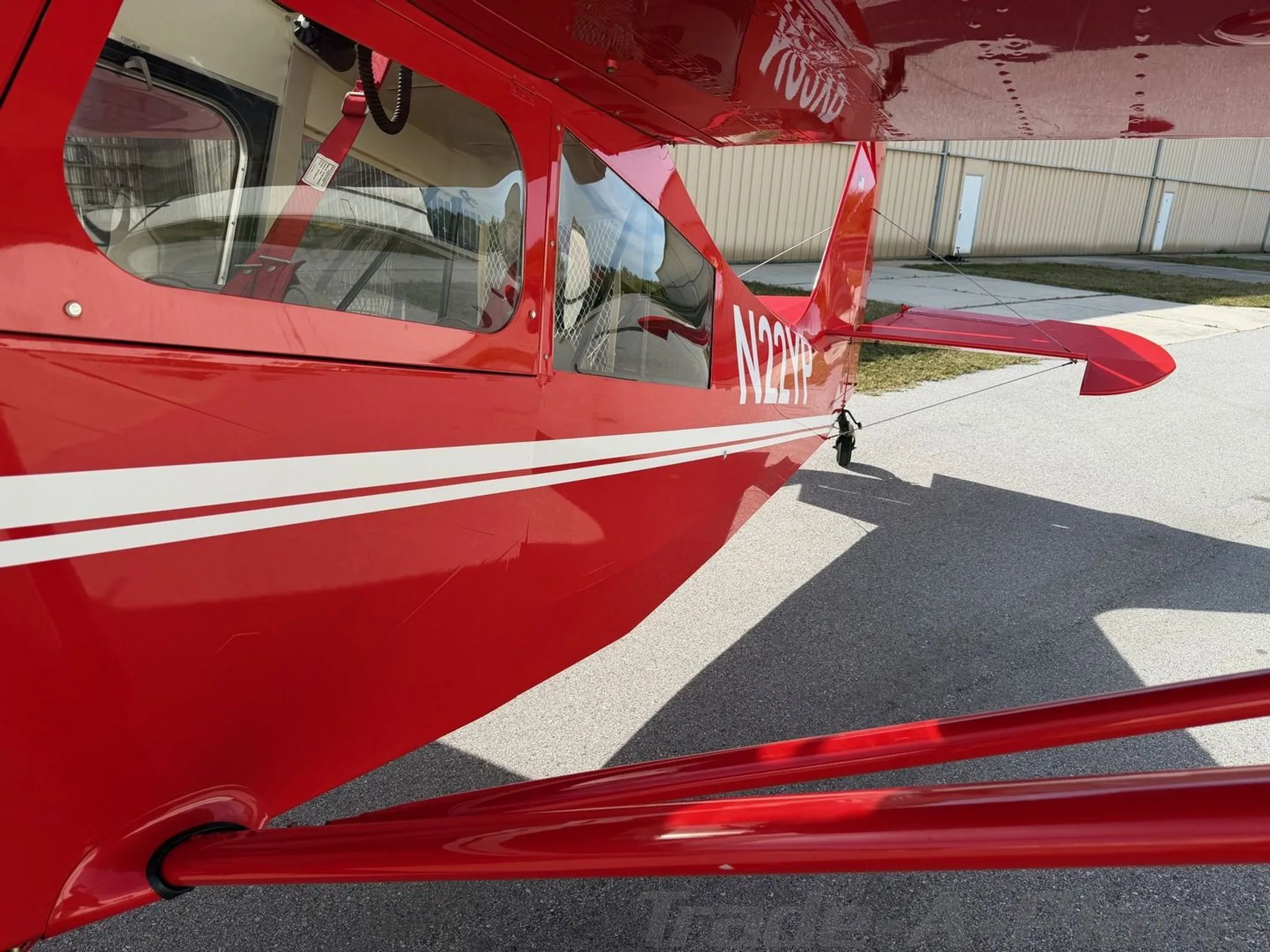 A side view of the red American Champion Xtreme Decathlon fuselage, showing the N22YP registration and white stripe.
