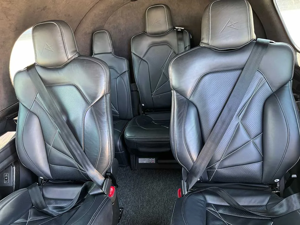 The black leather passenger seats with white stitching in the aircraft cabin.