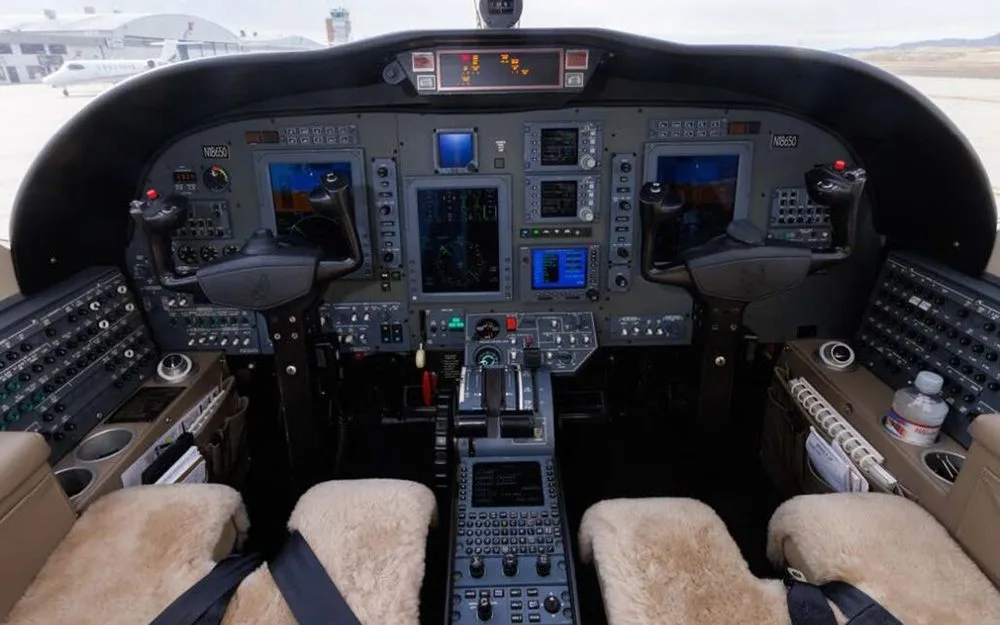 The cockpit of a business jet with multiple display screens and control panels.
