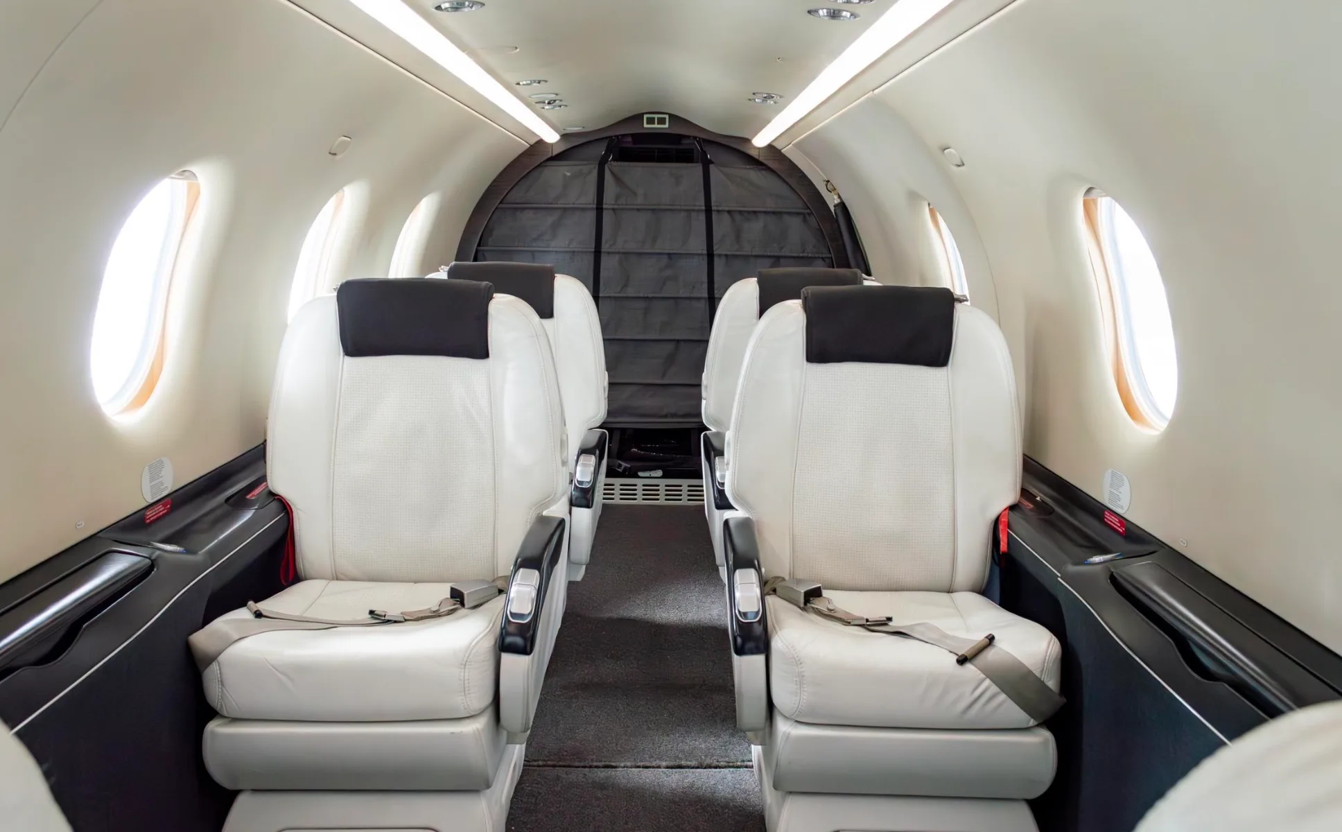Interior view of the Pilatus PC-12NG cabin with white leather seats.