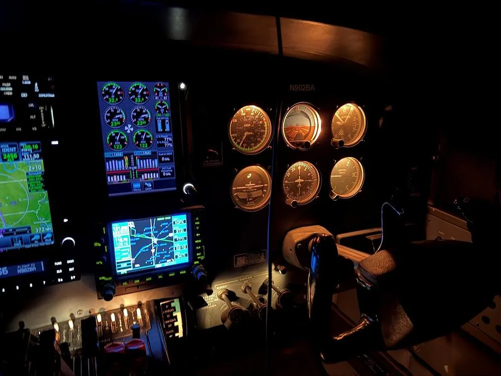 A dimly lit cockpit showing a mix of modern digital displays and classic analog gauges.