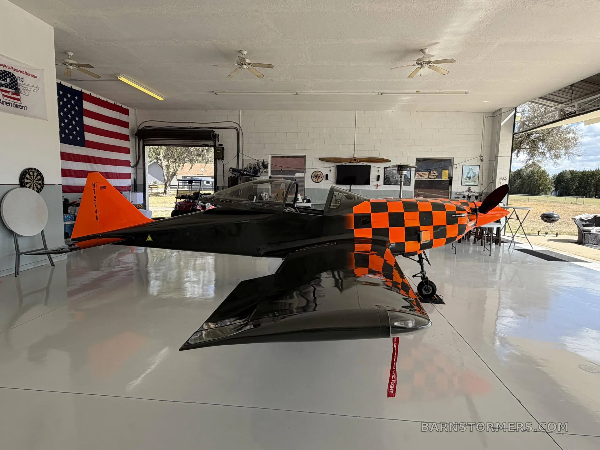 A black and orange checkered single-engine aircraft with tail number N7224A is parked inside a hangar.