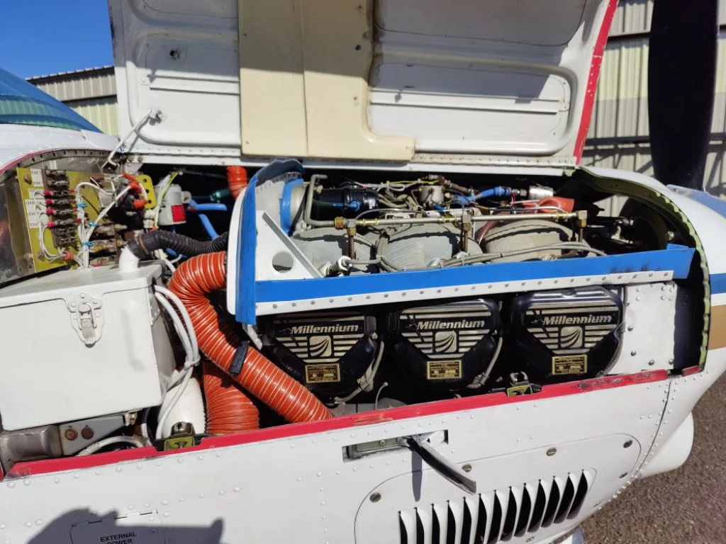 A close-up view of an aircraft engine compartment with the cowling open, revealing three 'Millennium' branded engine covers.
