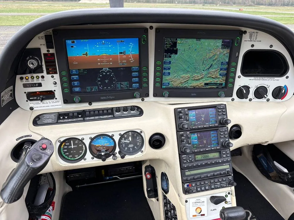 The cockpit of a Cirrus SR22 G3 aircraft features a glass panel with two large displays and traditional analog gauges.