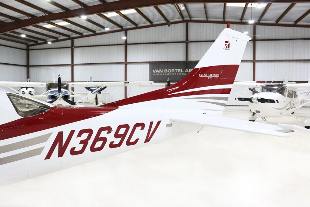 A close-up view of the tail section of the white and red Cessna Stationair TC aircraft (N369CV) in a hangar.