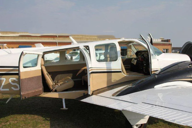 The open cabin and cockpit of a white and gold twin-engine aircraft, revealing tan seats and controls.
