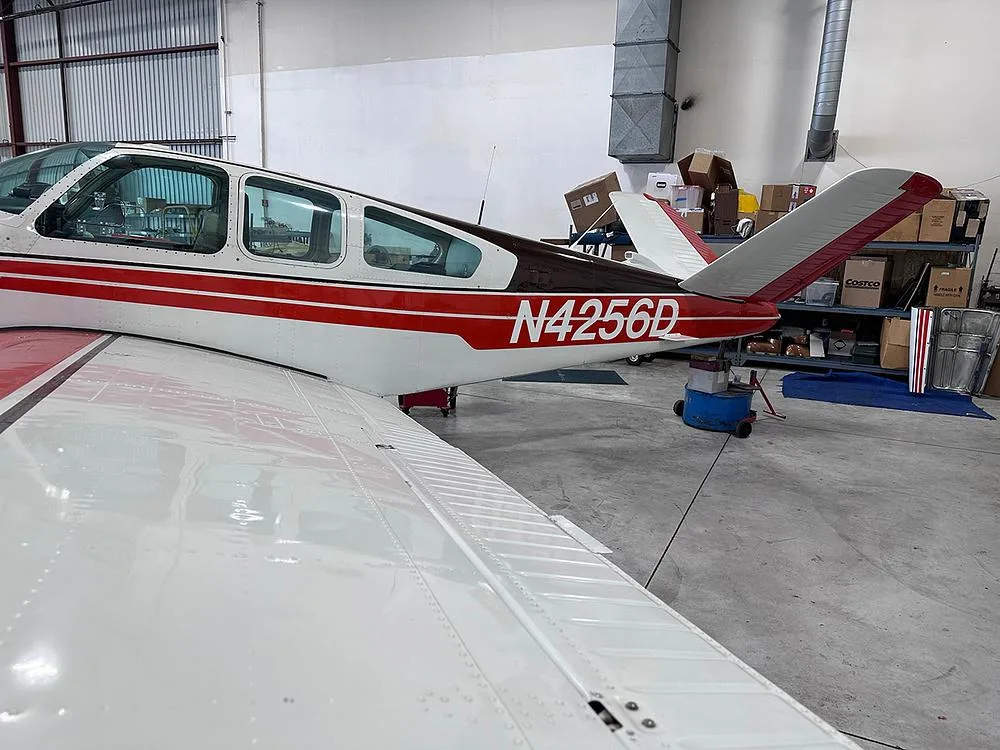 Rear view of a white and red aircraft with registration N4256D, parked in a hangar.