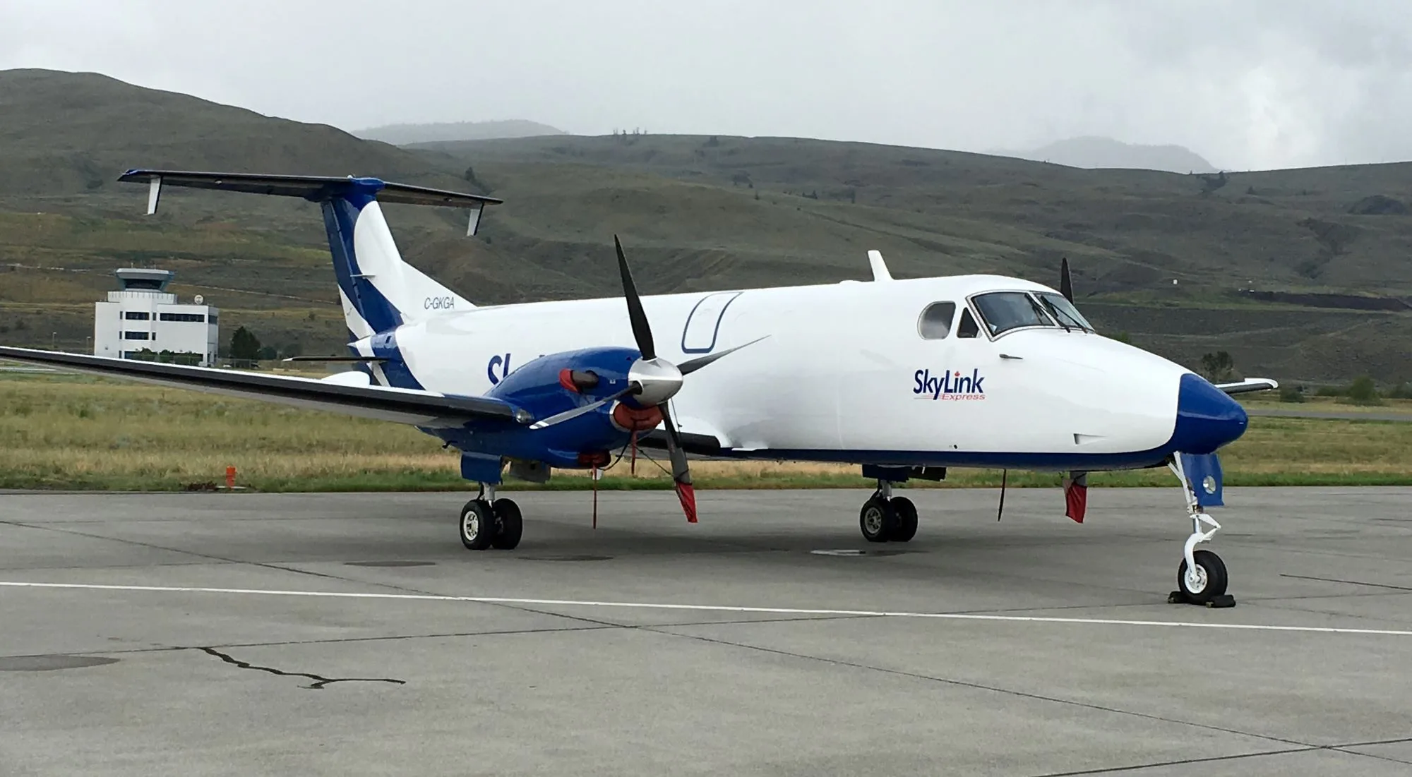 A SkyLink turboprop aircraft with blue and white livery parked on an airport tarmac.