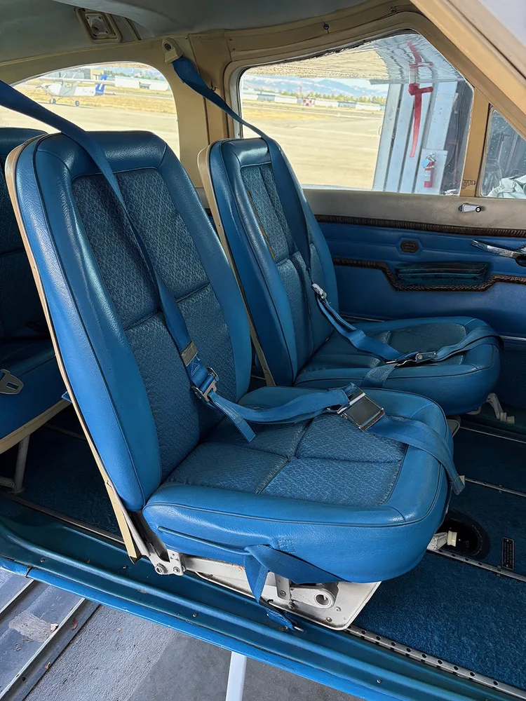 Two blue passenger seats in the cabin of a Cessna 177 aircraft, with seatbelts fastened.