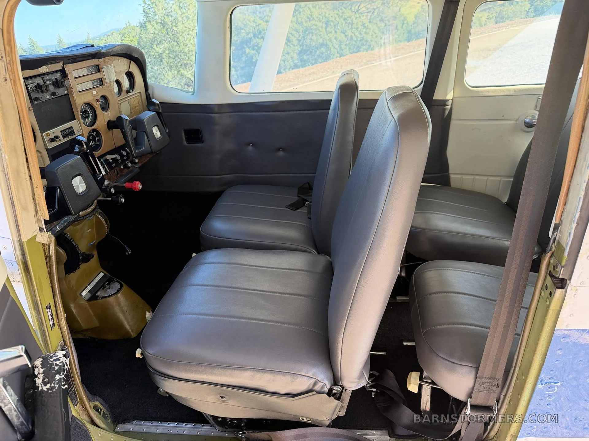 The aircraft cabin interior showing grey seats and the cockpit area in the foreground.