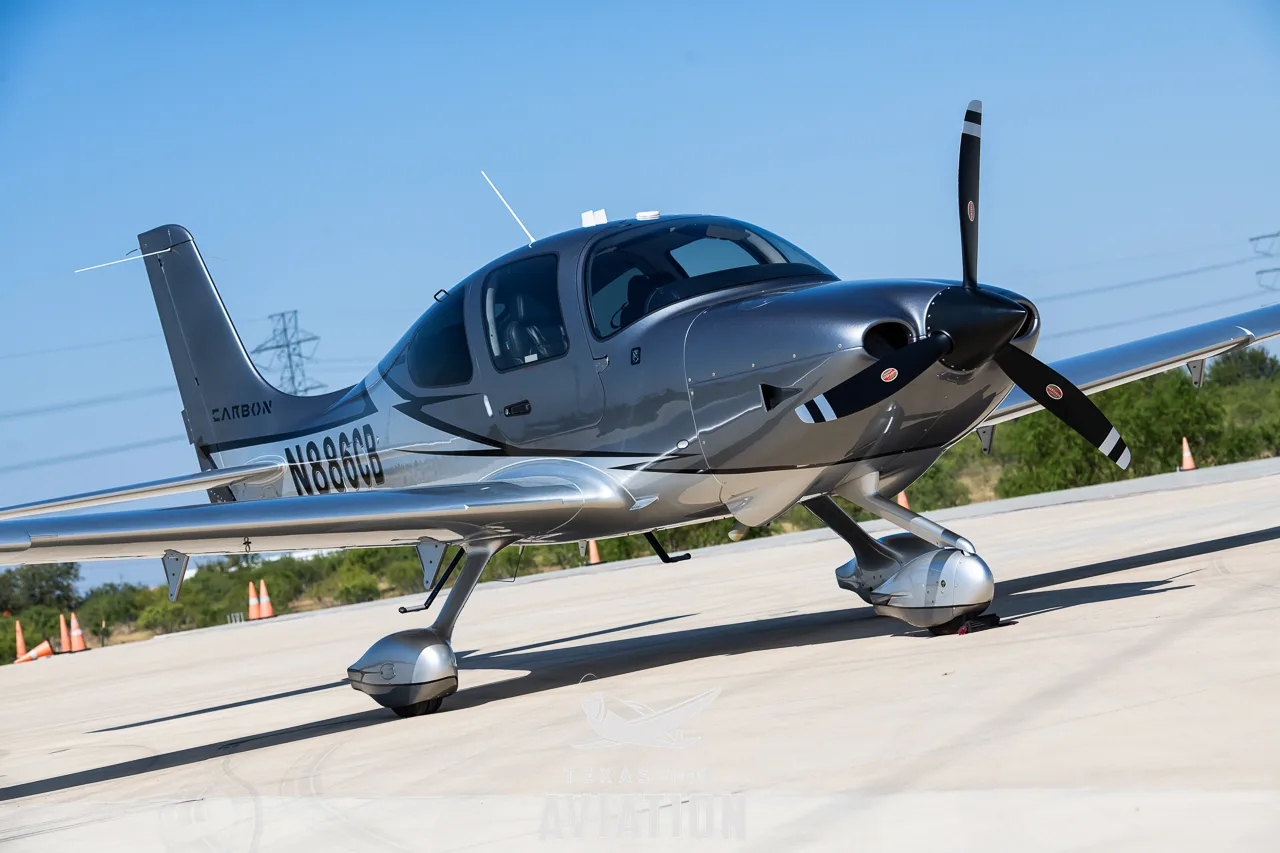 A silver and grey Cirrus SR22 aircraft with registration N886CB parked on an airfield.