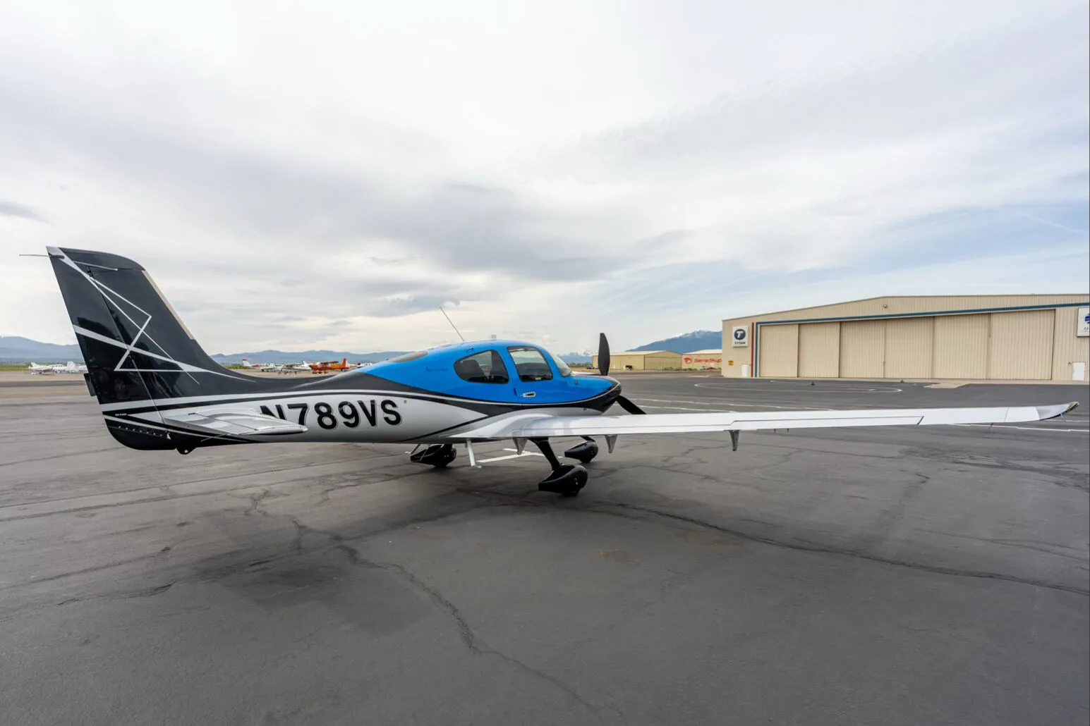 Three-quarter rear view of a black, blue, and silver single-engine aircraft with registration N789VS parked on an airfield.