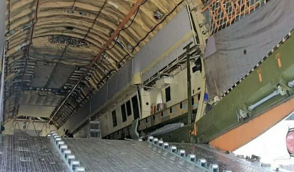 The interior of a large cargo aircraft's hold is visible, showing a loading ramp and internal structural elements.