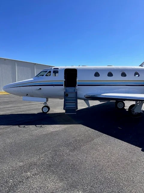 A side view of the N700JC business jet with its integrated airstair door extended, parked on an asphalt surface.