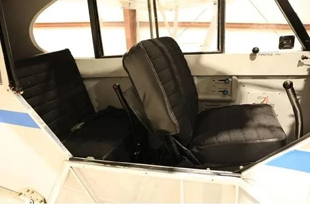 The simple black fabric seats and interior of a small aircraft cabin.