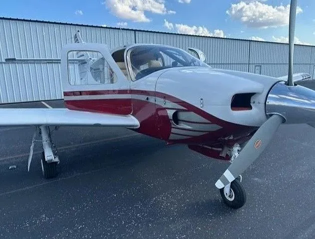 A front-side view of the white and red aircraft N1292J with its door open, parked on an asphalt surface.