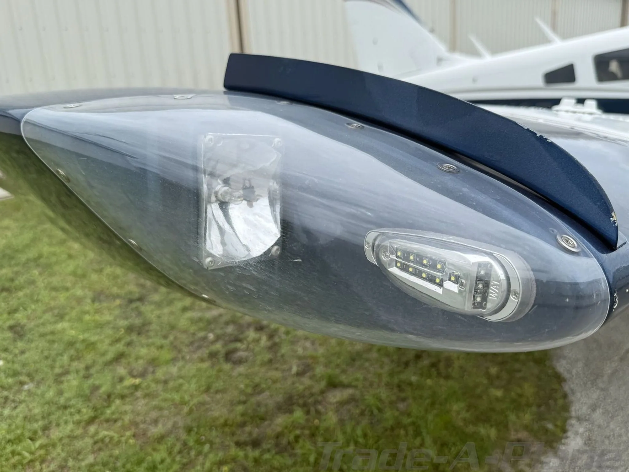 Close-up of the wingtip with an LED navigation light and a strobe light on the white and blue aircraft.