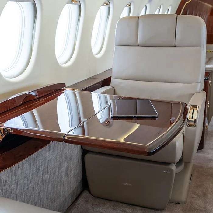 A leather seat with a wood table extended in the aircraft cabin.