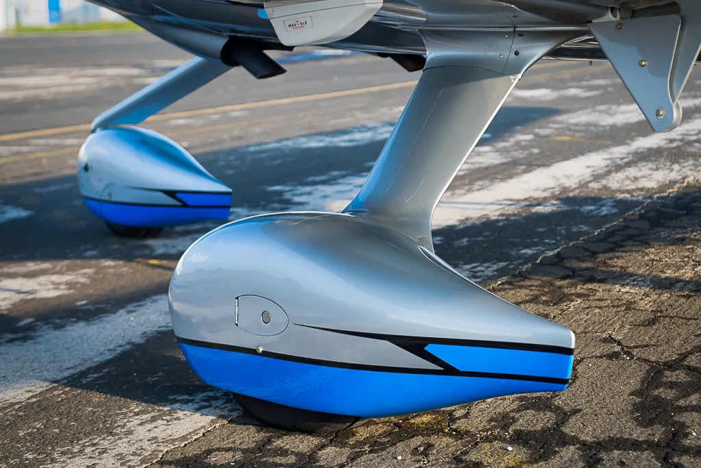 A close-up view of the blue and silver main landing gear fairings of the Cirrus SR22T GTS Carbon aircraft.