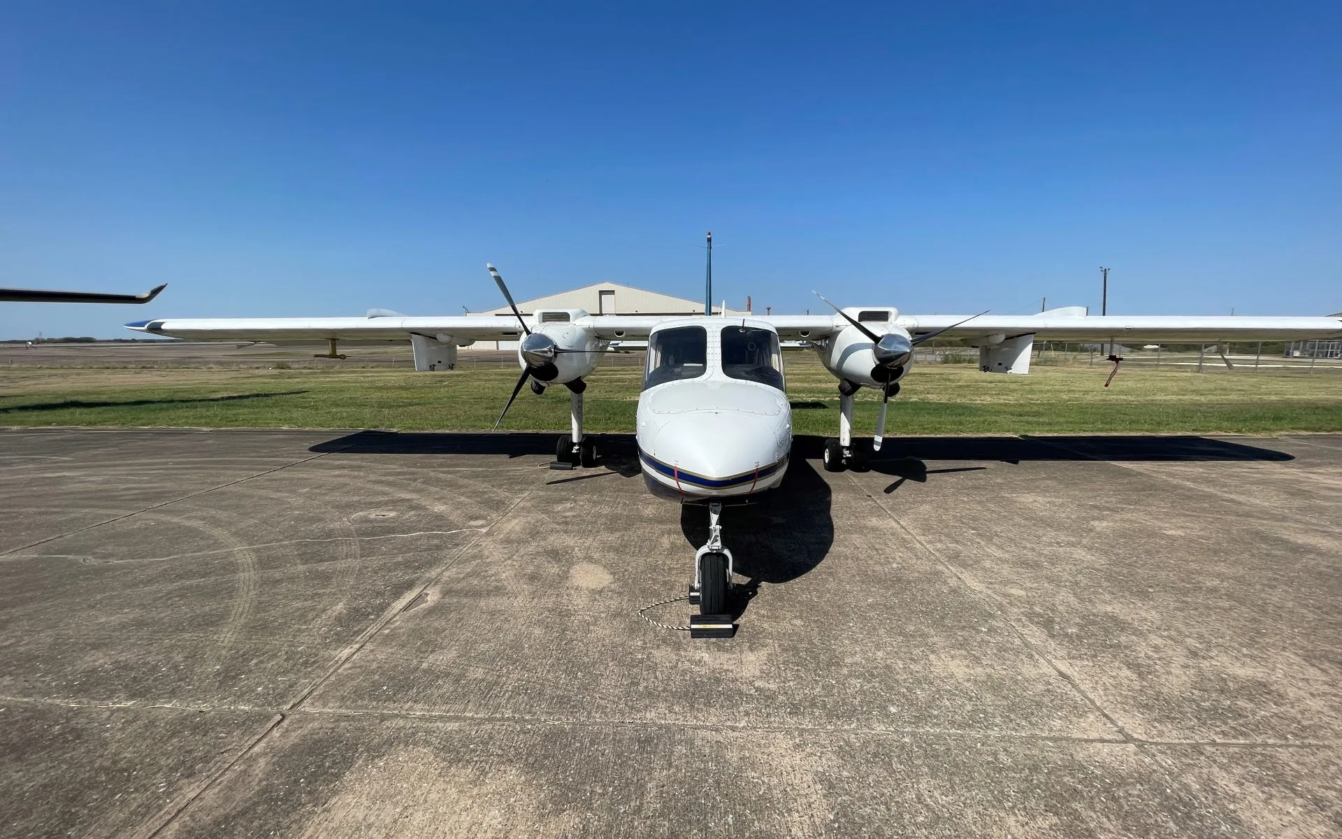 Front view of a white and blue aircraft on the tarmac.