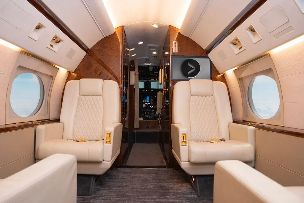The luxurious interior cabin of a private jet features cream leather seats and polished wood accents.
