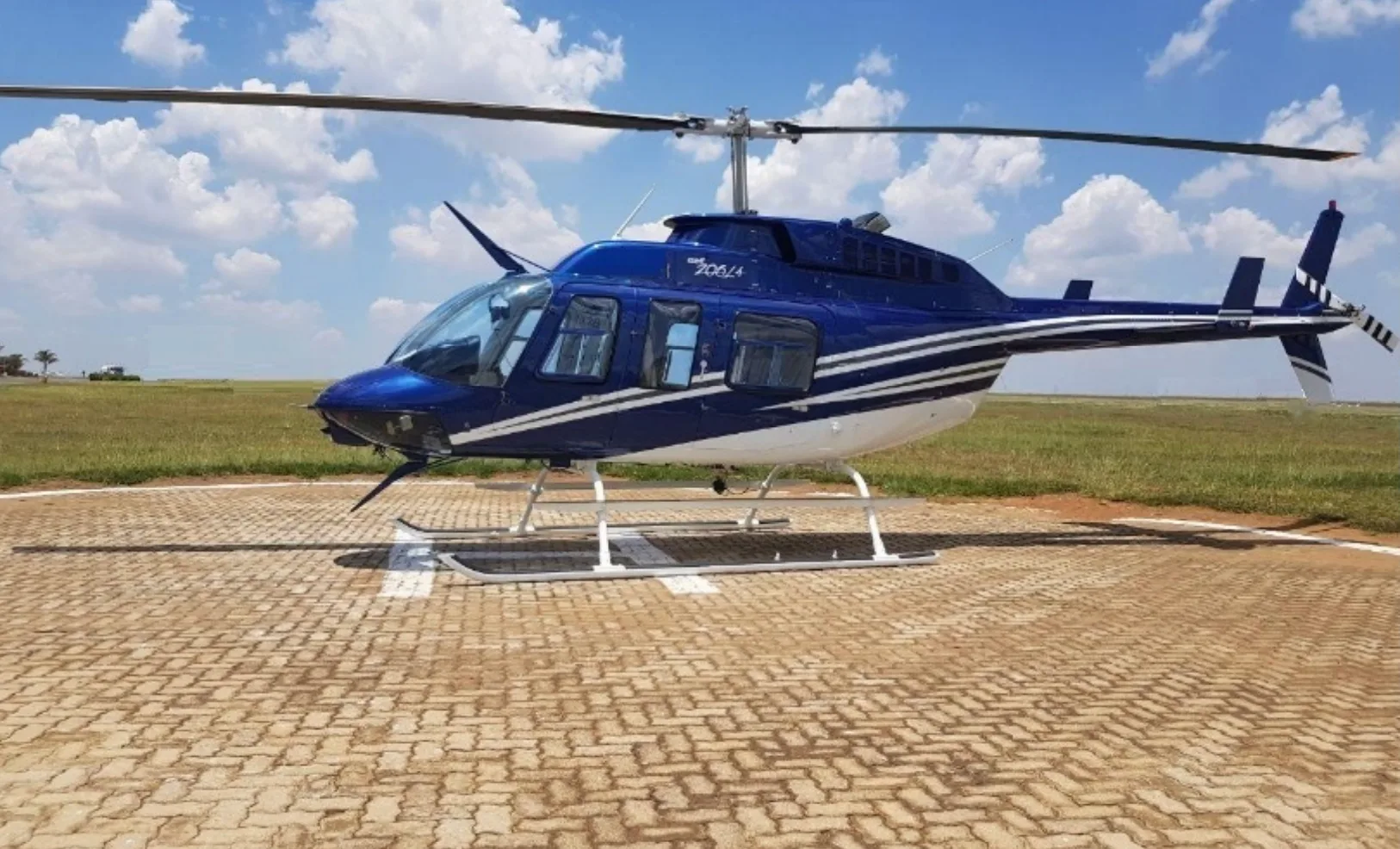 A blue Bell 206L-4 helicopter parked on a runway.
