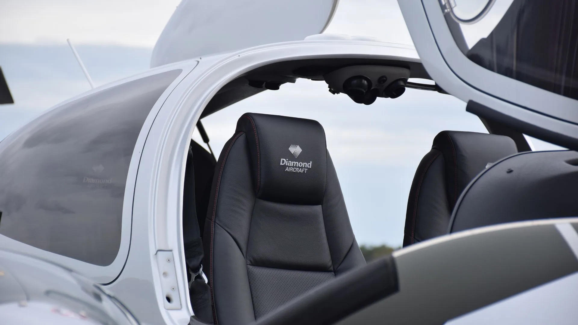 The black leather interior seats of a Diamond DA62 aircraft, with the "Diamond Aircraft" logo embroidered on the headrest.