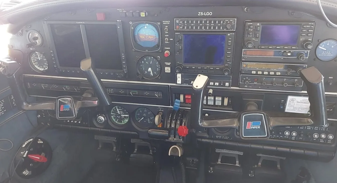 The cockpit instrument panel of a Piper aircraft, showing various gauges, screens, and controls.