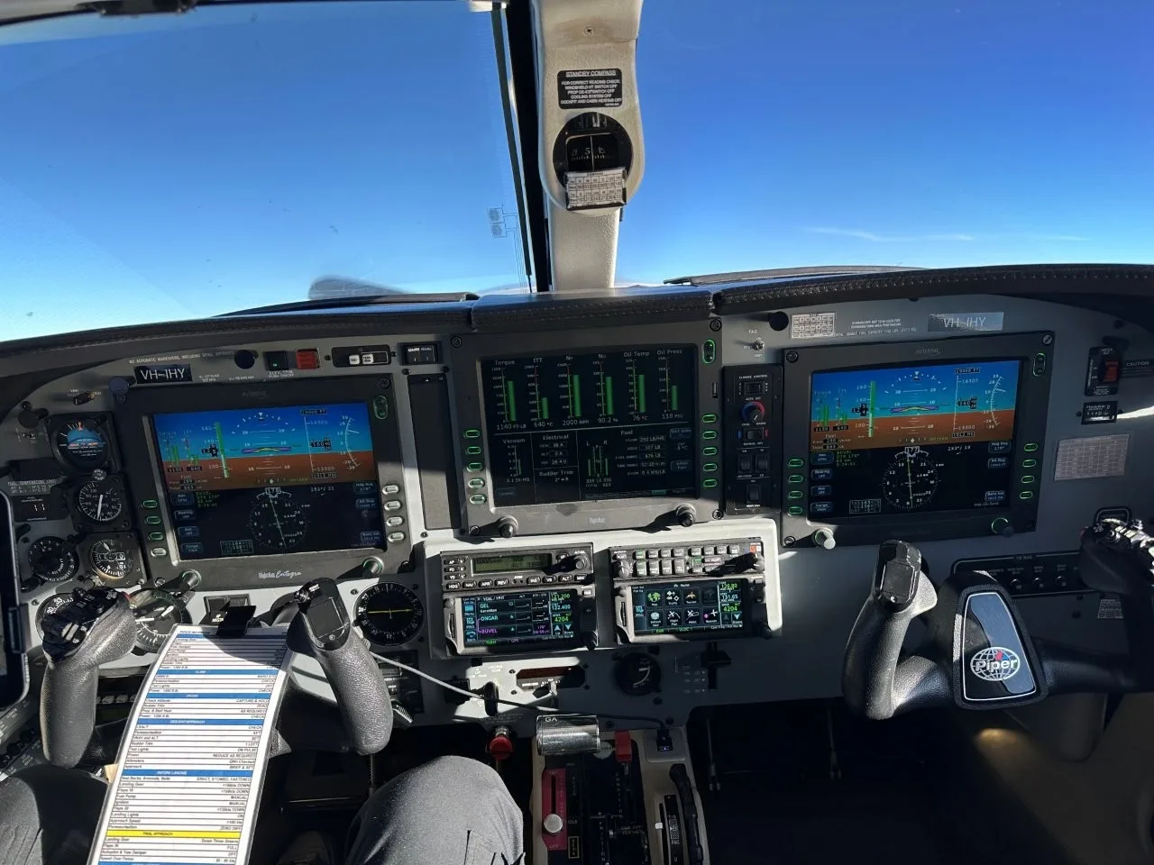 The cockpit of a Piper Meridian, showing the glass panel displays, controls, and a checklist on the yoke.