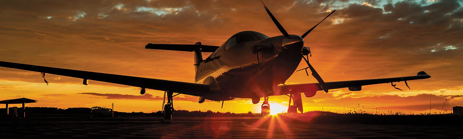 Pilatus PC-12 aircraft silhouetted against a sunset.