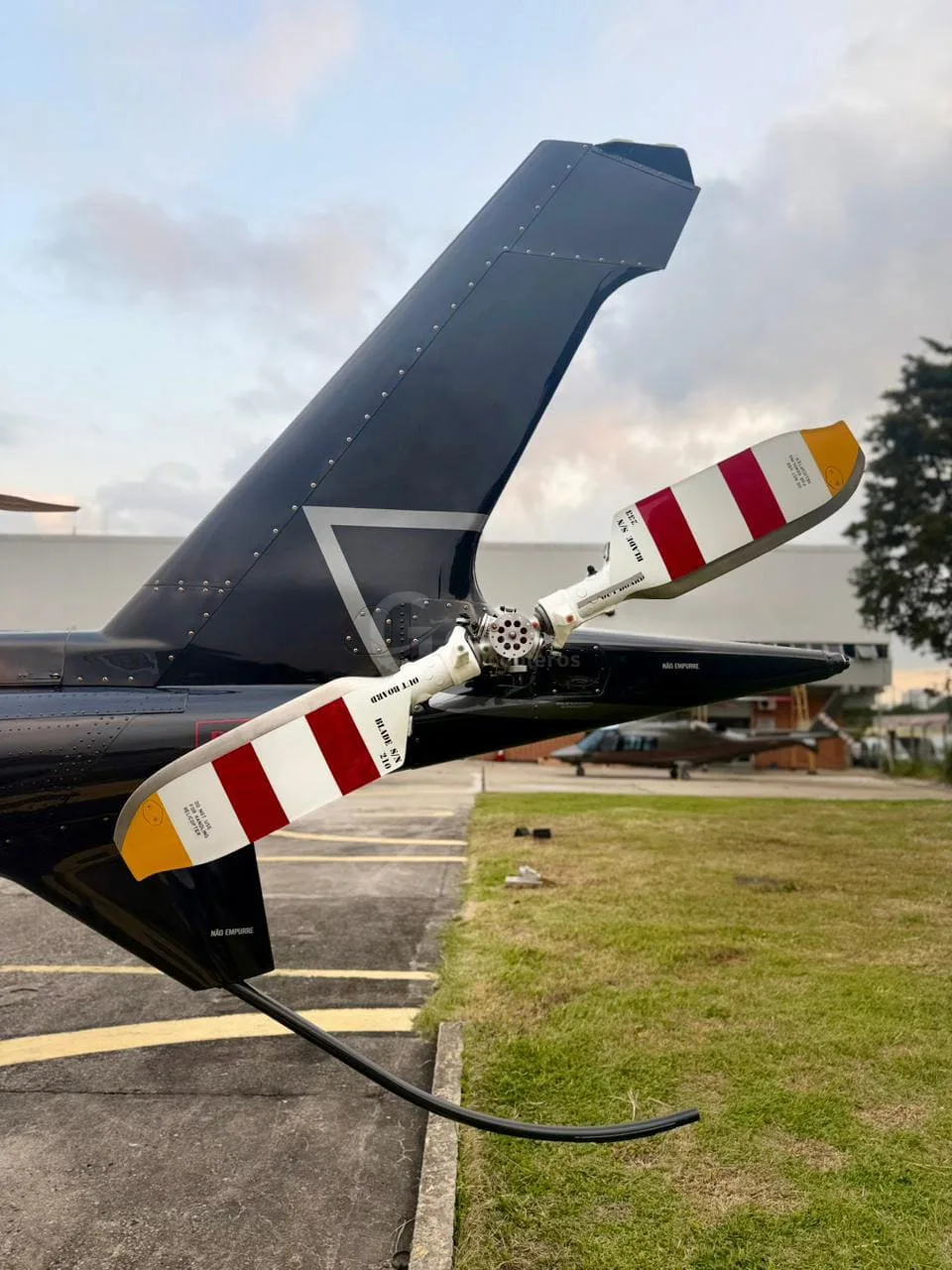 A close-up view of the red, white, and yellow striped tail rotor of a black helicopter.