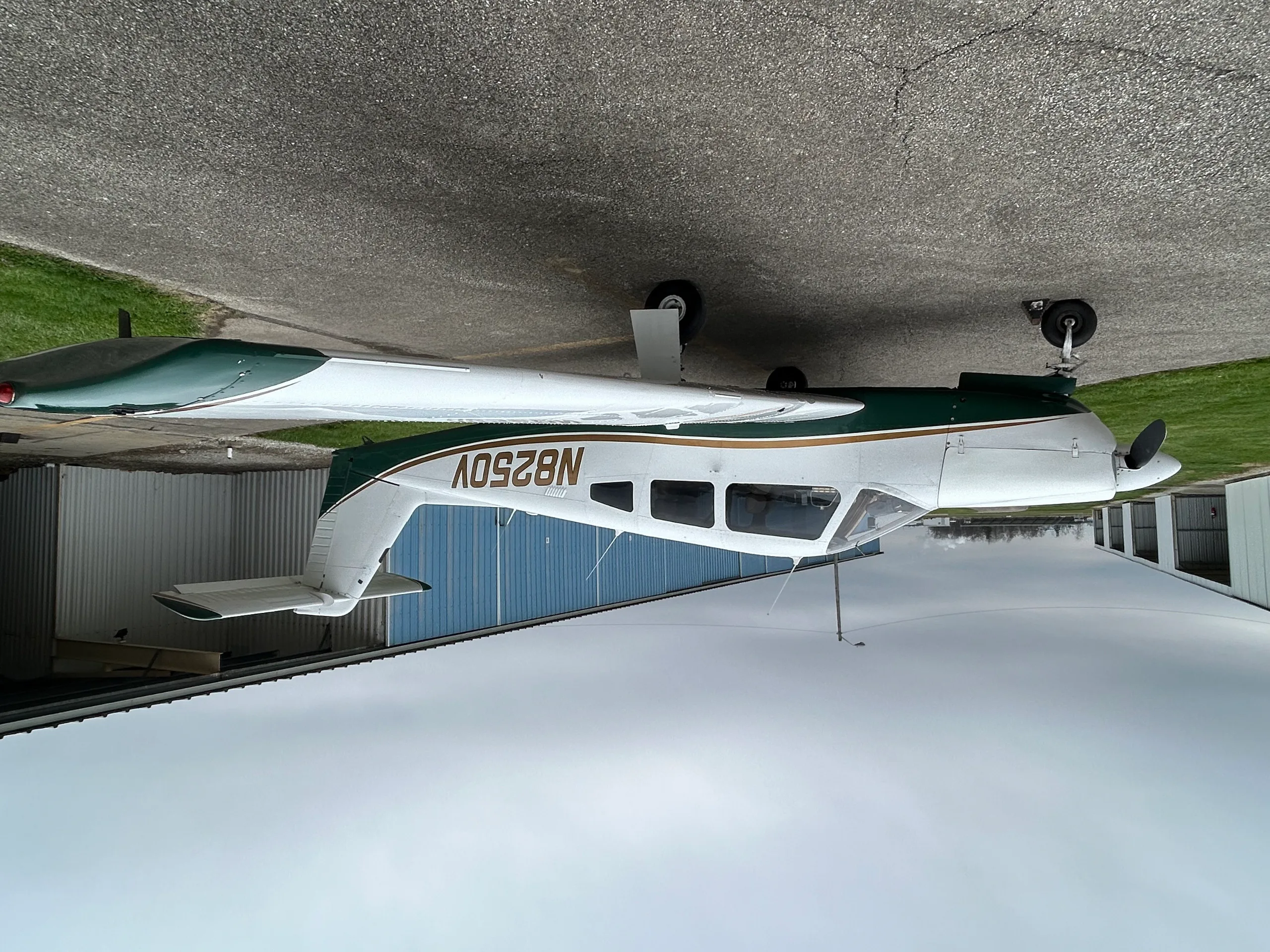 A side view of a white and green single-engine aircraft, N8250V, parked on an asphalt ramp.