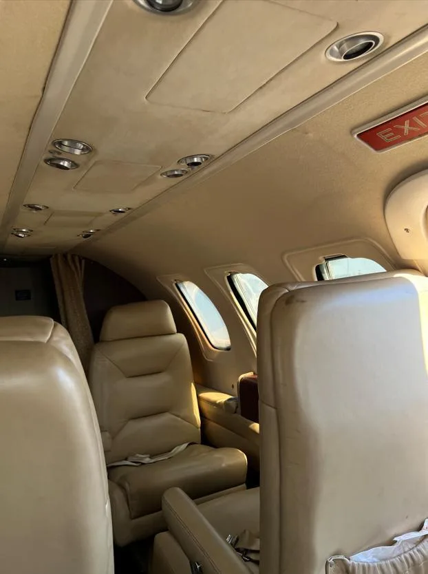 A view of the tan leather seats and overhead panel in the interior cabin of a business jet.