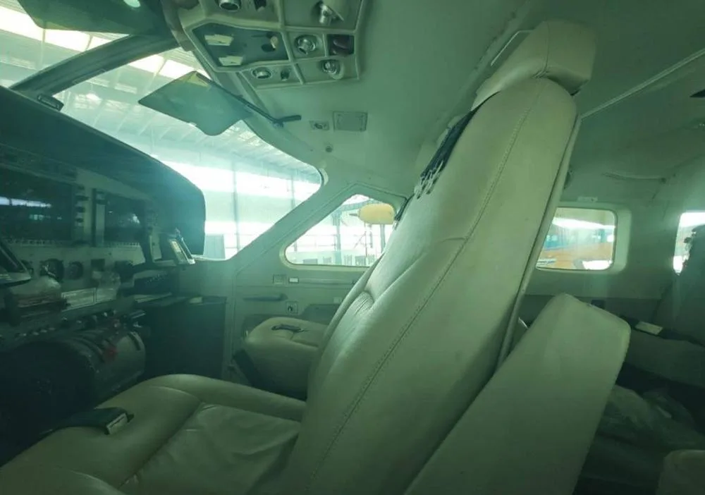 The light-colored pilot's seat and a partial view of the instrument panel and controls inside the cockpit of the seaplane.