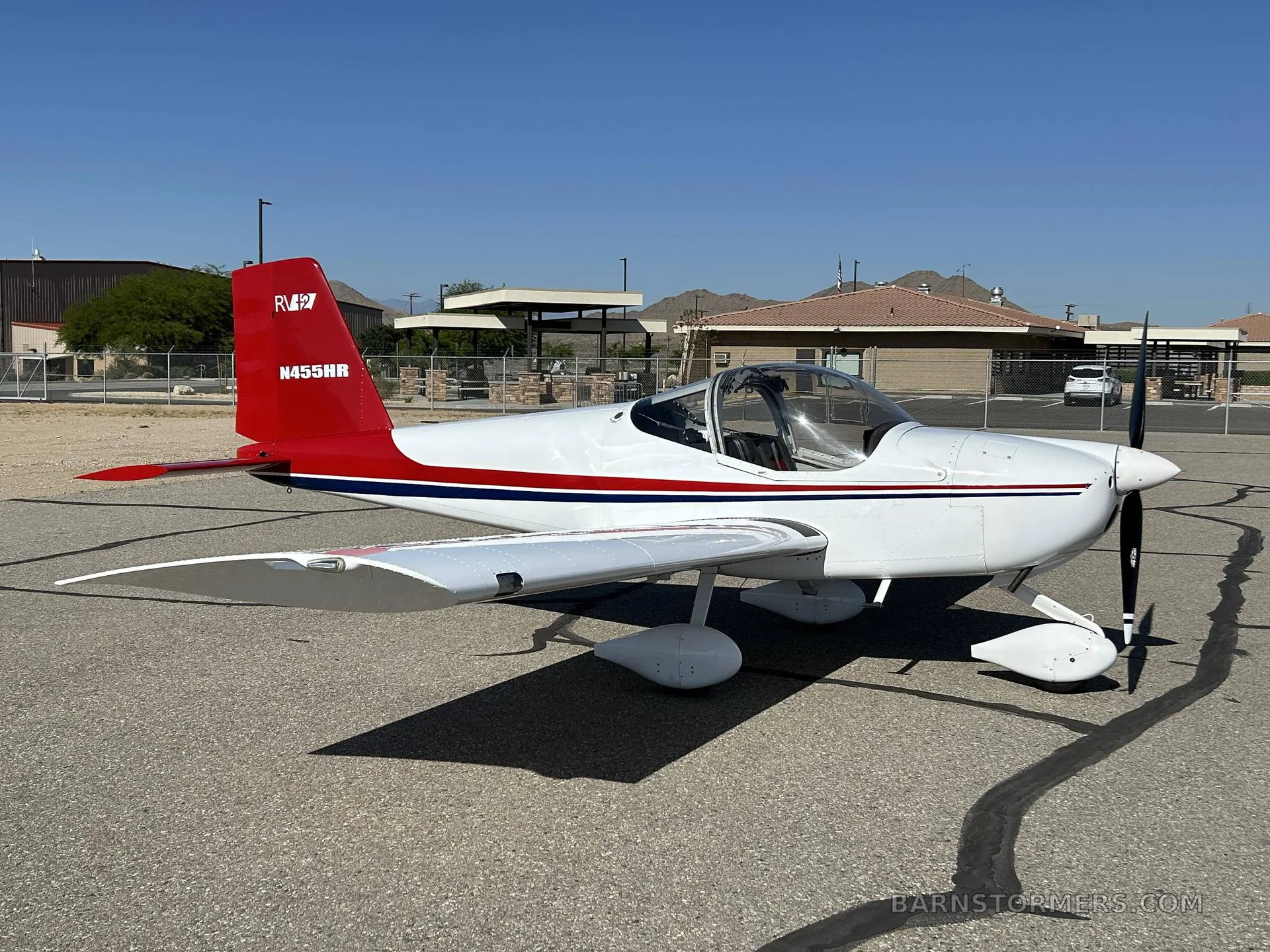 A white and red Van's RV-7 aircraft, registration N455HR, is parked on an asphalt tarmac, viewed from the front-right side.