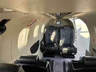View of the interior of an aircraft cabin with black leather seats.