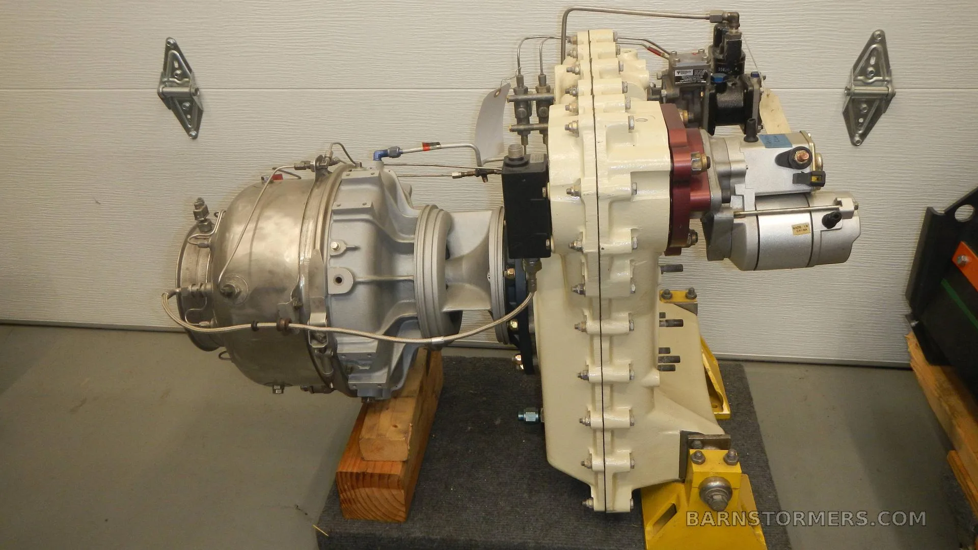 A turboprop or turboshaft aircraft engine mounted on a yellow stand in a workshop.