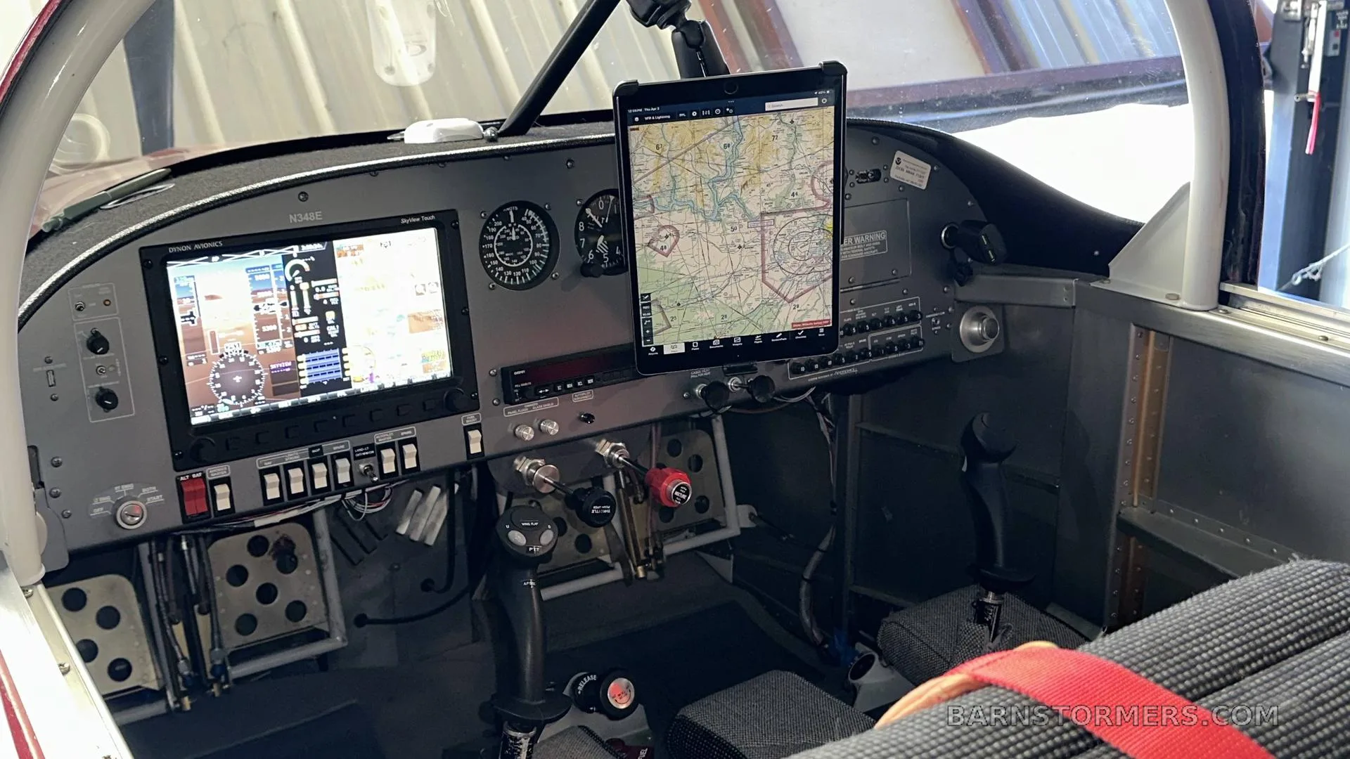 The cockpit of a small aircraft features a glass panel display, traditional gauges, and an iPad mounted on the dashboard.