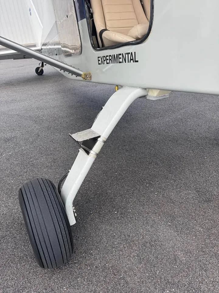A close-up view of the nose landing gear and the "EXPERIMENTAL" marking on the fuselage of the aircraft.