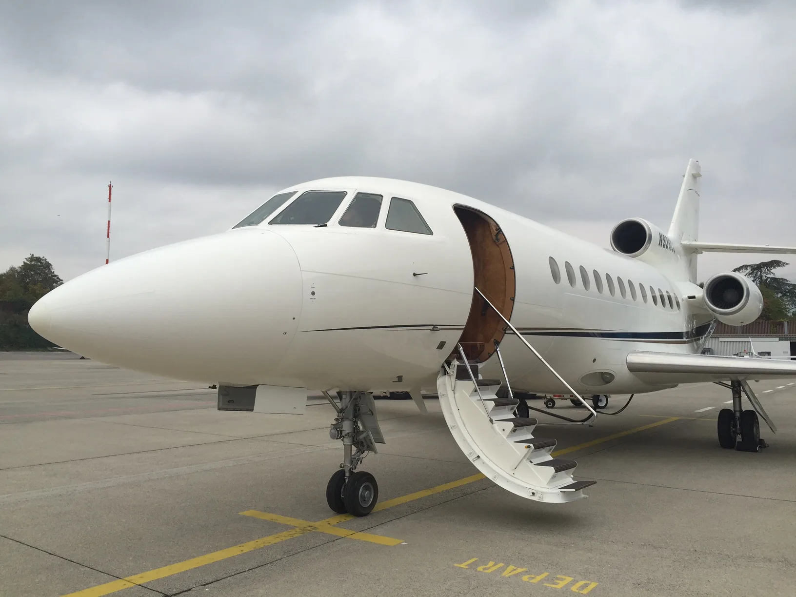 A white aircraft with an open door and stairs extended on the tarmac.
