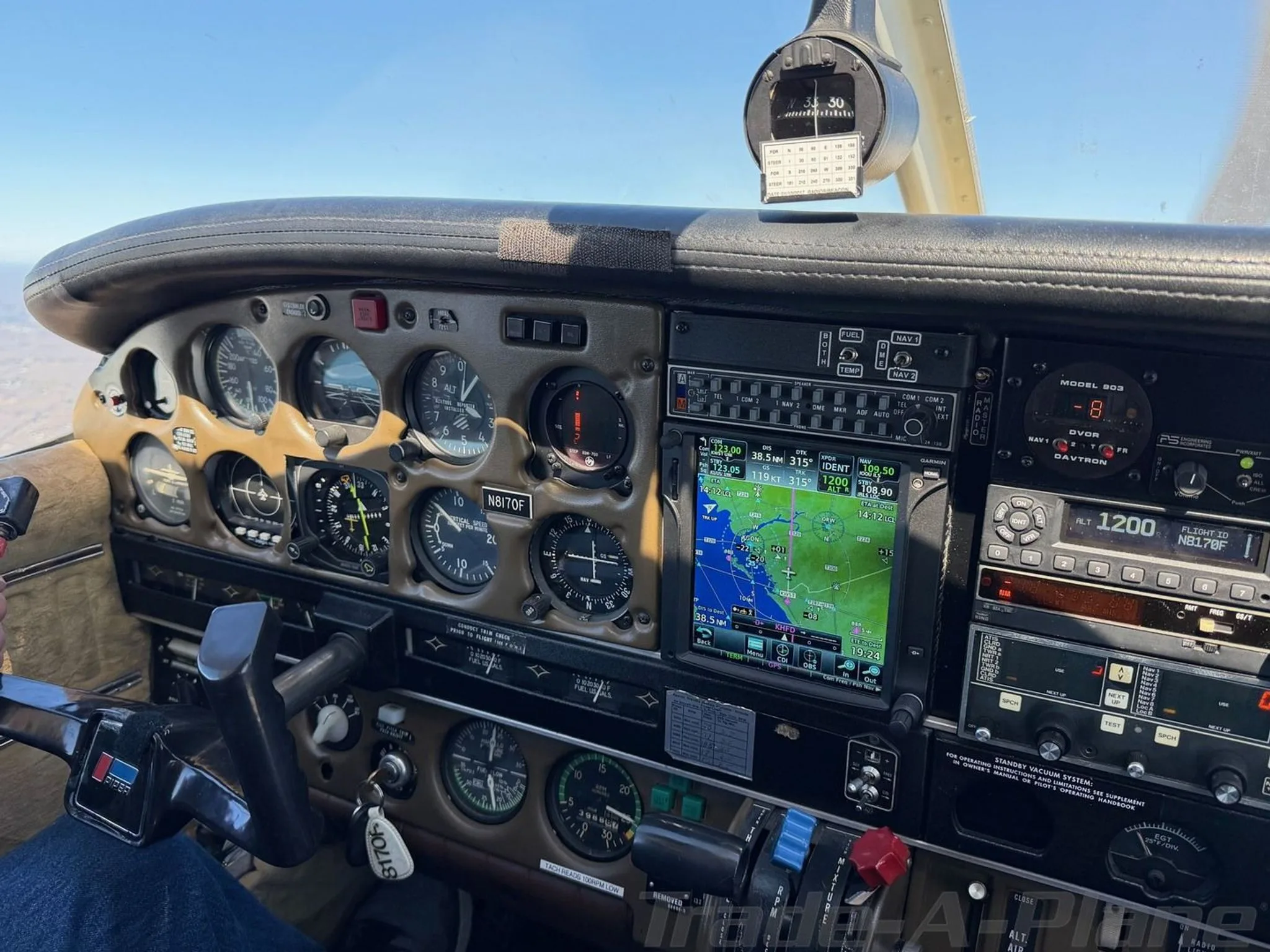 A close-up view of the Piper Cherokee aircraft's instrument panel, showing gauges, a GPS display, and the N-number N8170F on a gauge.