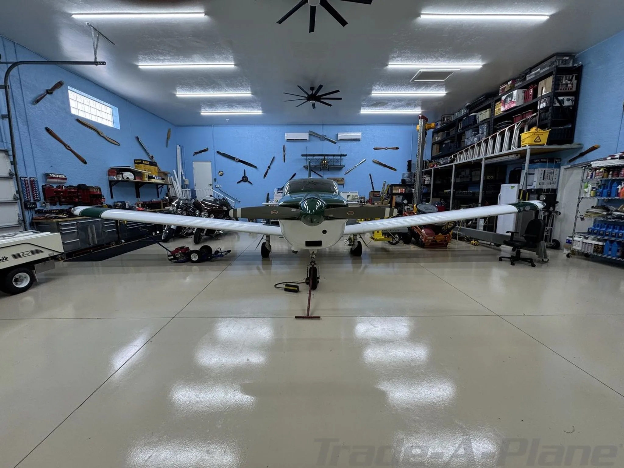 A front view of a green and white single-engine aircraft (N88AV) parked inside a hangar.