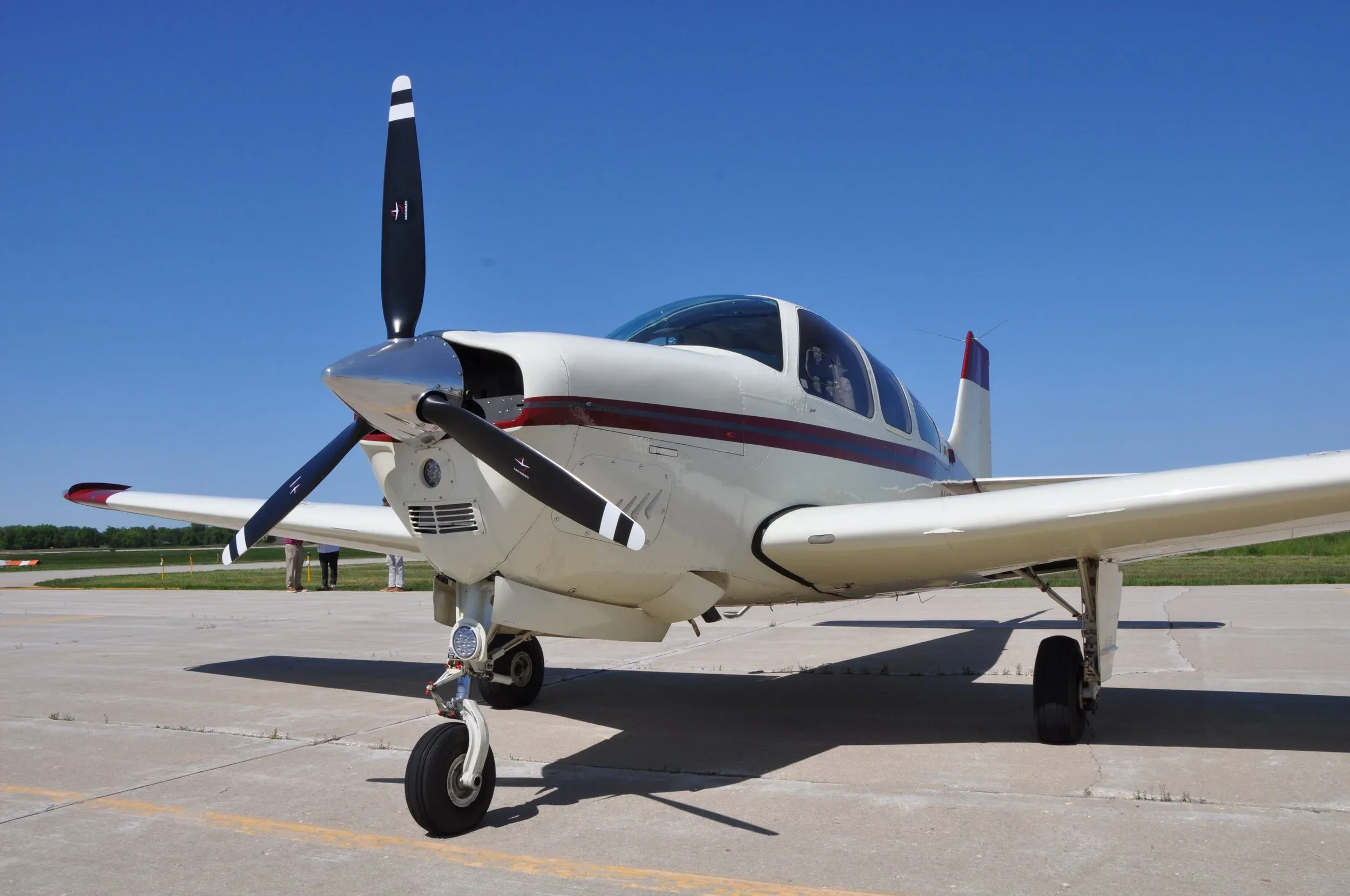 A close-up front-left view of the white and red propeller aircraft on the tarmac.
