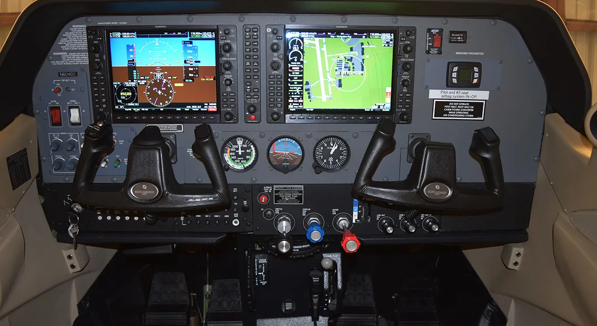 The cockpit of an aircraft featuring a modern glass panel with multiple digital displays and traditional analog gauges.