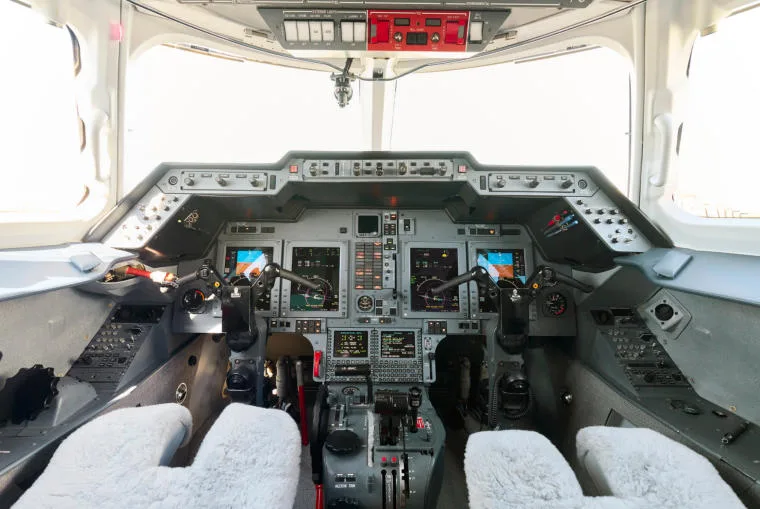 The modern glass cockpit of a business jet with multiple display screens and controls.