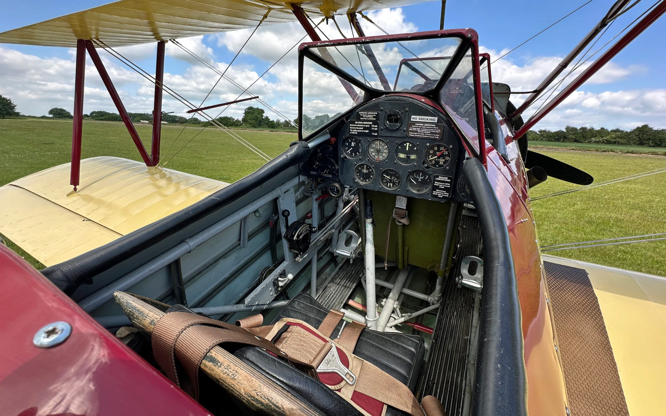 The open cockpit of a Stearman biplane showing the instrument panel, controls, and seat.