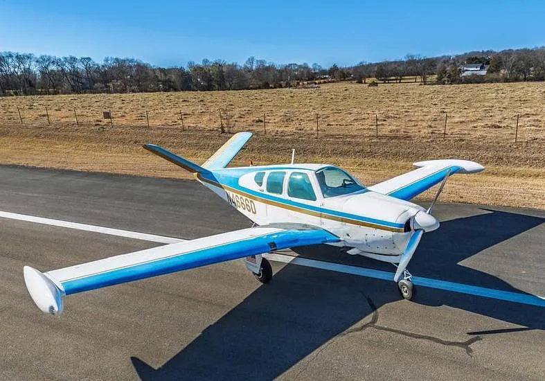 A white and blue single-engine aircraft with registration N4666D parked on an asphalt runway.